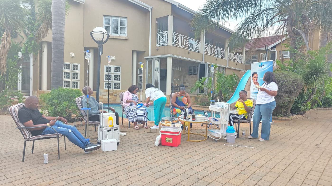Guests relaxing poolside while receiving IV drip treatments at a Med-Pro wellness event